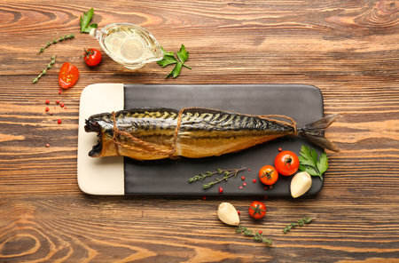 Board with tasty smoked mackerel fish on wooden background