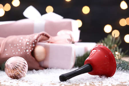 Christmas bell on table with snow against blurred background