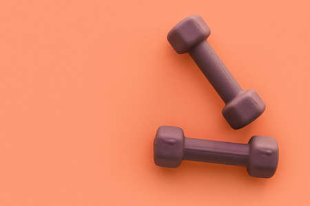 Stylish dumbbells on orange background
