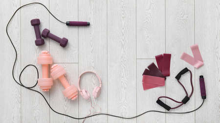 Stylish sport equipment and headphones on wooden background