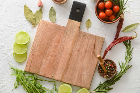 New cutting board with lime, tomatoes and spices on light backgroundの写真素材