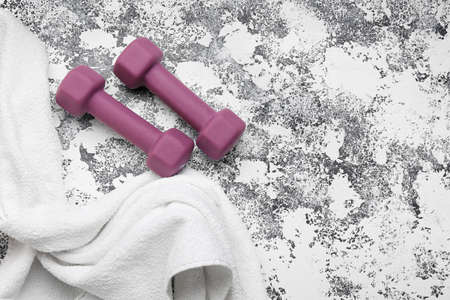Stylish dumbbells and towels on light grunge backgroundの写真素材