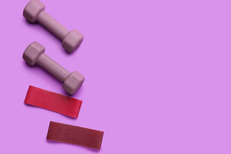 Stylish dumbbells and elastic bands on purple backgroundの写真素材