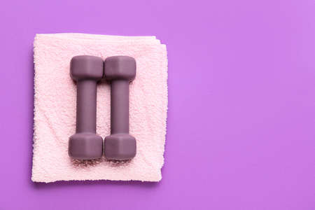 Stylish dumbbells and towel on purple backgroundの写真素材