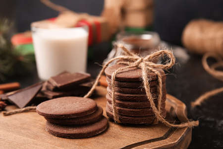 Wooden board with tasty chocolate cookies and on black backgroundの写真素材