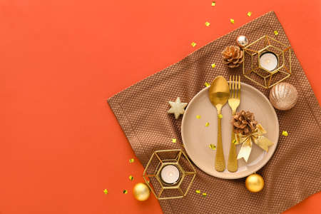 Beautiful Christmas table setting with decor and candles on orange backgroundの写真素材