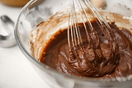 Bowl with fresh chocolate dough on white wooden background, closeupの写真素材