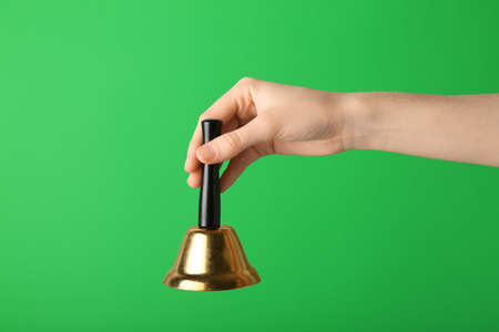 Female hand with Christmas bell on green background, closeupの写真素材
