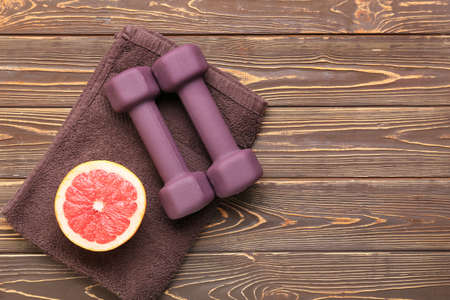 Stylish dumbbells, towel and grapefruit on wooden backgroundの写真素材