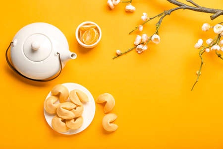 Tasty fortune cookies with tangerines and Chinese tea on color backgroundの写真素材