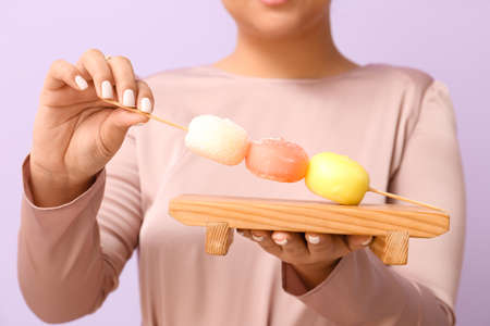 Beautiful Asian woman with tasty Japanese mochi on color background, closeupの写真素材