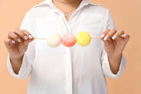 Beautiful Asian woman with tasty Japanese mochi on color background, closeupの写真素材