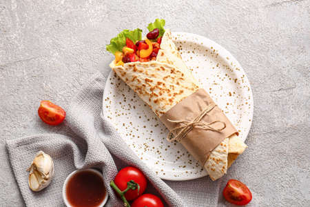 Plate with delicious burrito and sauce on gray backgroundの写真素材