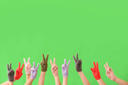 Women in warm gloves showing victory gesture on green backgroundの写真素材