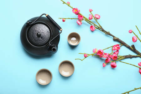 Chinese tea with blooming tree branch on color backgroundの写真素材