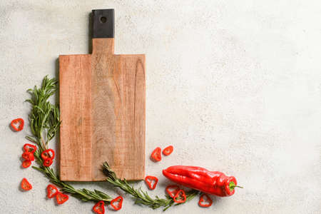 Wooden cutting board with chili pepper and rosemary on white backgroundの写真素材