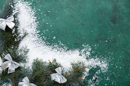 Fir branches, Christmas bows and snow on color background