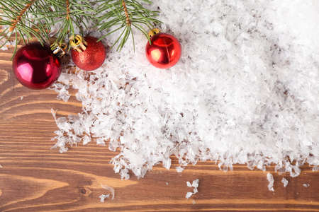 Christmas balls, snow and fir branches on wooden backgroundの写真素材