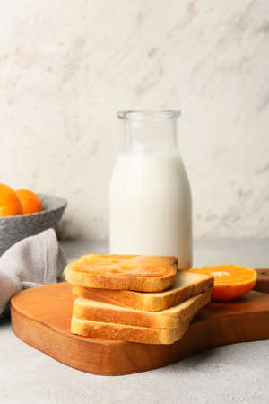 Tasty toast with tangerine jam and bottle of milk on tableの写真素材