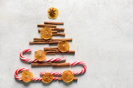 Christmas tree made of cinnamon, candy canes and dried citrus slices on light backgroundの写真素材