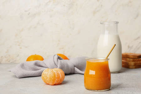 Jar of tasty tangerine jam and milk on light backgroundの写真素材