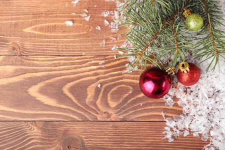 Christmas balls, snow and fir branches on wooden backgroundの写真素材