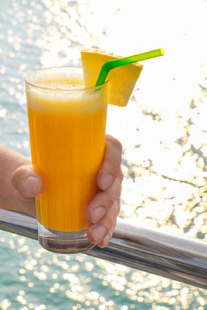 Male hand with glass of fresh tropical cocktail at sea resort
