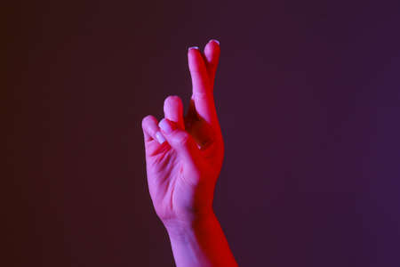 Woman with crossed fingers on dark color background, closeupの写真素材