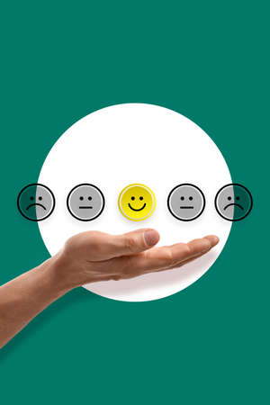 Male hand and different emoticons on green background. Satisfaction concept