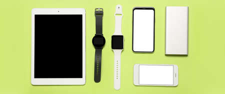 Set of modern devices with power bank on green background, top view