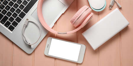 Different modern devices with power bank on pink wooden background, top viewの写真素材
