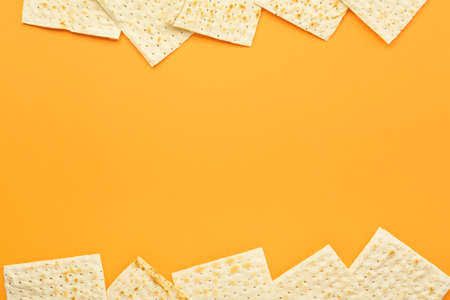 Frame made of Jewish flatbread matza for Passover on orange background