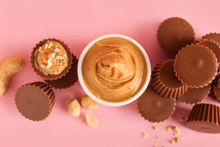 Tasty peanut butter cups on color background