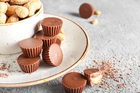 Plate with tasty peanut butter cups on grunge background