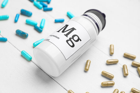 Bottle with different magnesium capsules on light wooden background, closeupの写真素材