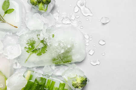 Fresh vegetables frozen in ice on light backgroundの写真素材
