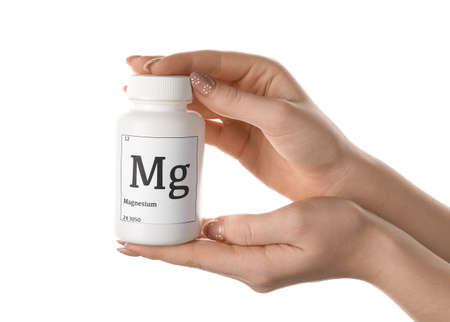Female hands with bottle of magnesium pills on white background, closeupの写真素材