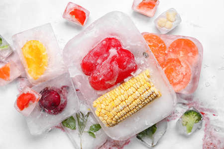 Fresh vegetables frozen in ice on light backgroundの写真素材