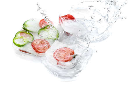 Fresh vegetables frozen in ice with splash of water on white backgroundの写真素材