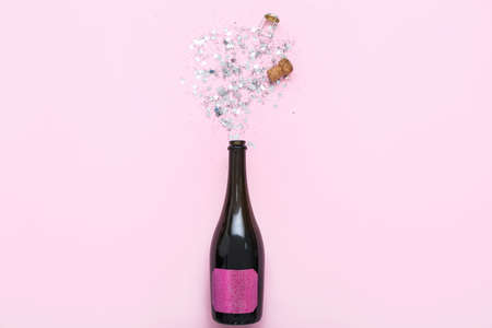 Composition with bottle of champagne and beautiful confetti on pink backgroundの写真素材
