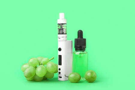 Modern vape mod, oil and grapes on green backgroundの写真素材