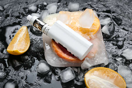 Modern vape mod, orange and ice cubes on black background, closeupの写真素材