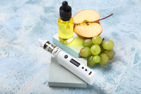 Modern vape mod, oil and fruits on blue backgroundの写真素材