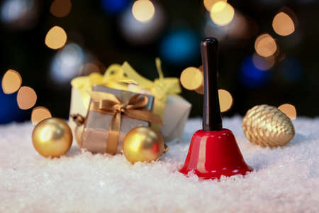 Christmas bell, decorations and gifts on snow against blurred backgroundの写真素材
