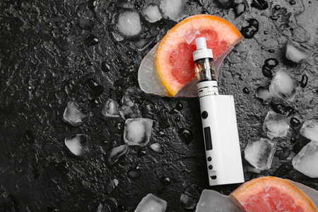 Modern vape mod, grapefruit and ice cubes on black backgroundの写真素材