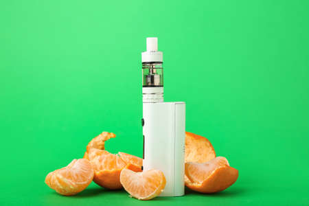 Modern vape mod and tangerine on green backgroundの写真素材
