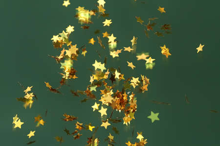 Flying golden confetti on green background