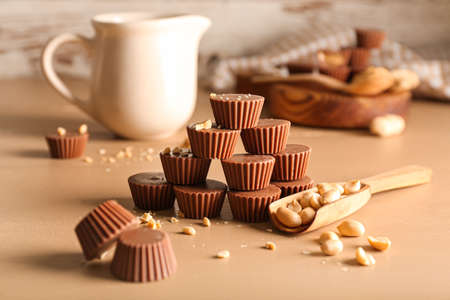 Tasty chocolate candies with peanut butter on color background