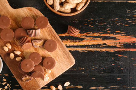 Board with tasty chocolate candies with peanut butter on dark wooden backgroundの写真素材