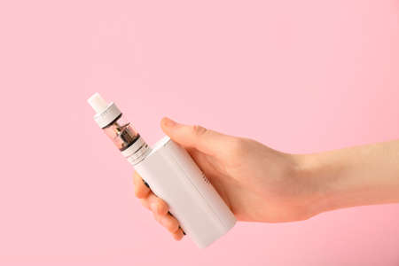 Female hand with modern vape mod on pink background